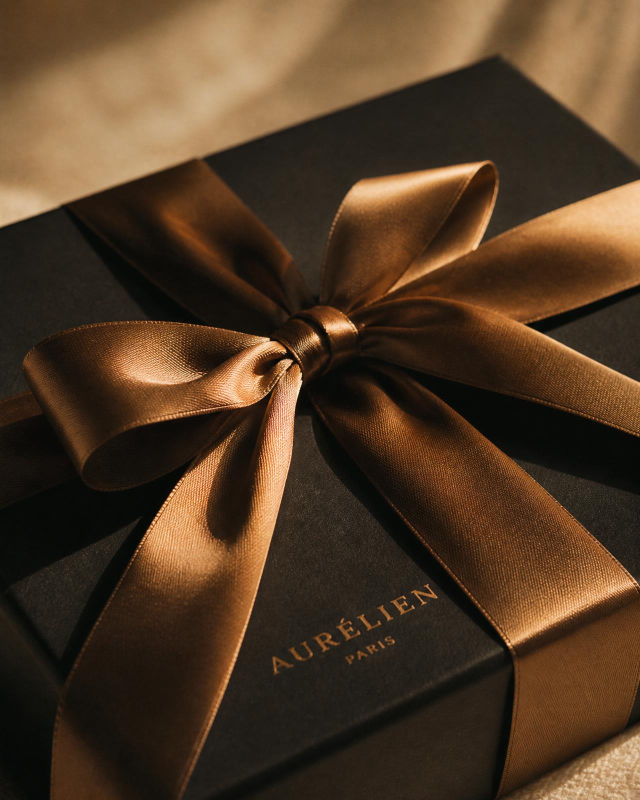 Silk-gloved hands untying a bronze ribbon from a matte black shopping box