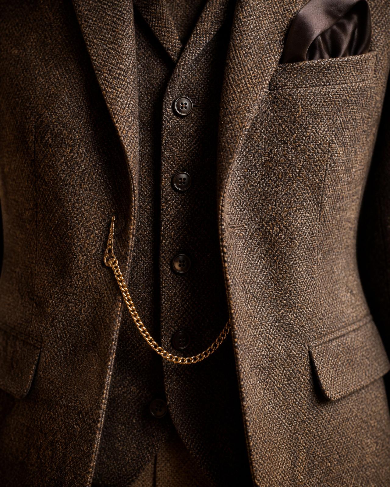 Chest-to-waist crop of a vintage brown tweed three-piece suit with an espresso silk pocket square and gold pocket watch chain